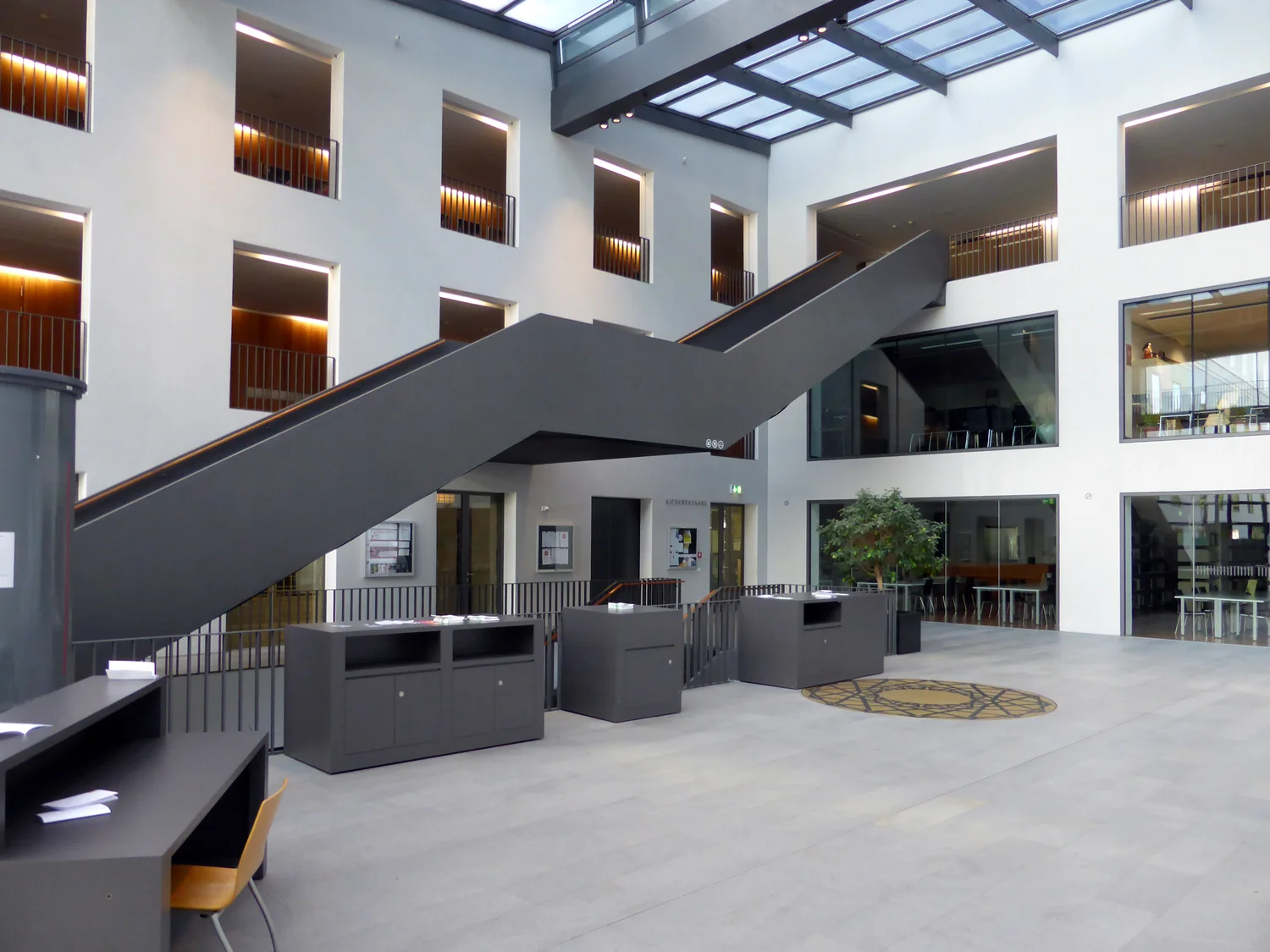 Entrance hall of Mozarteum University in Salzburg, with a broad staircase and balconies beneath a glass roof