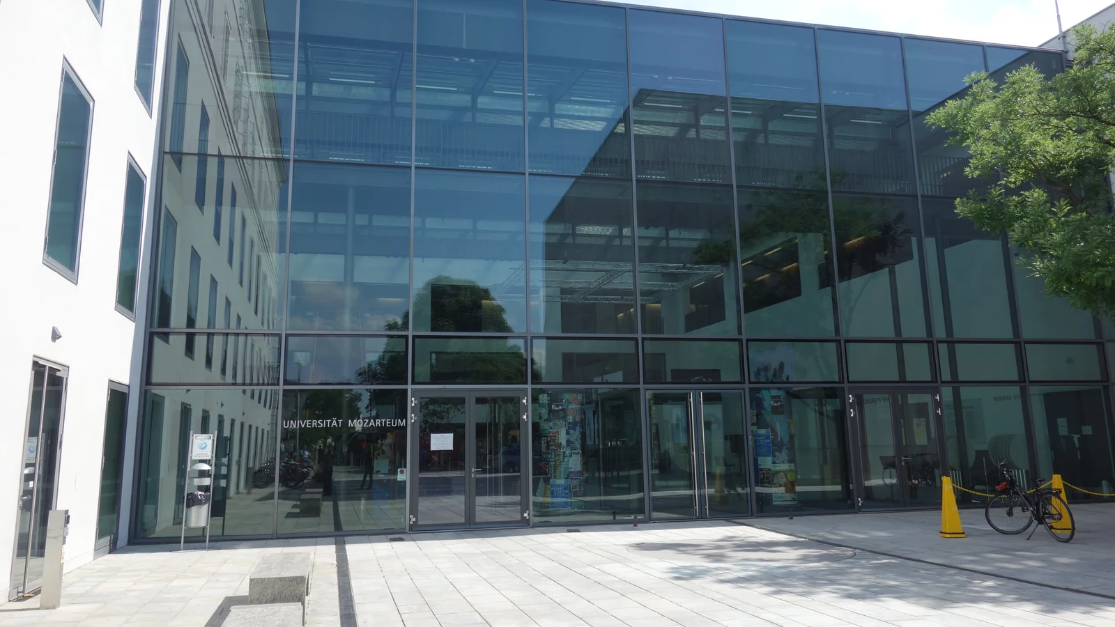 Glass entrance façade of Mozarteum University at Mirabellplatz in Salzburg, with the university name beside the doors