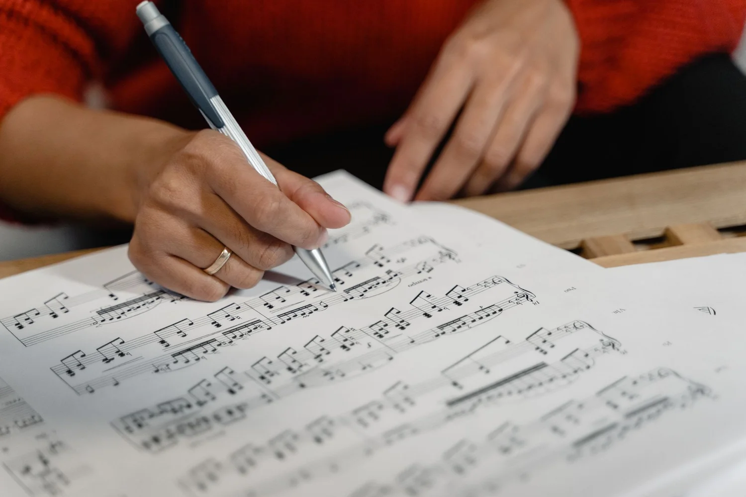 Close-up of hands making notes on a printed musical score