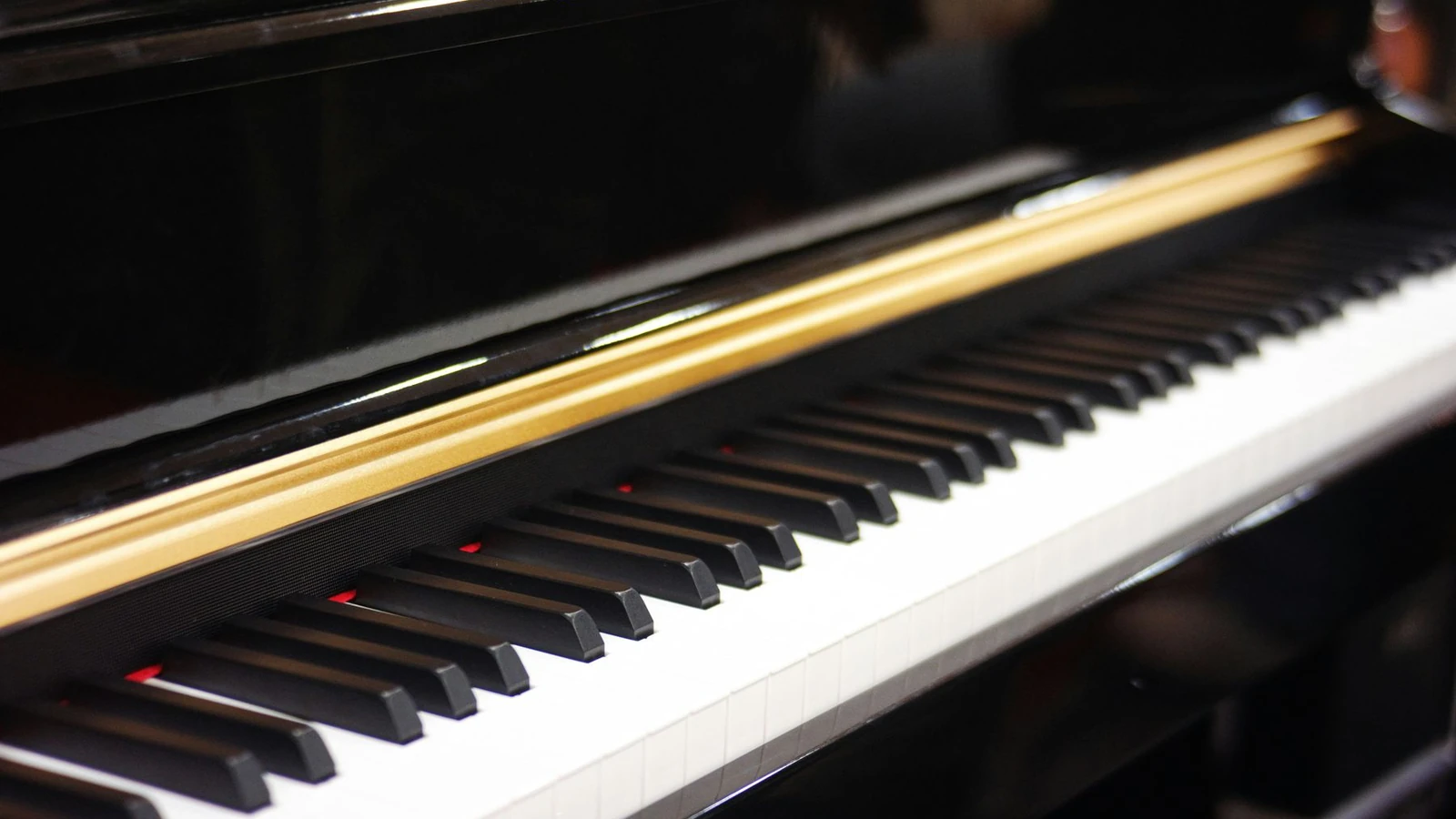 A close view of piano keys beneath a polished dark case and gold trim